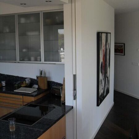 Raumteiler als raumhohe Weißlack-Schiebetür mit türbreitem Glasausschnitt und Design-Türgriff im Glas, in die Wand laufend, Tür geöffnet