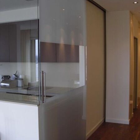 Raumhohe Glasschiebetür mit verdeckter Schiene, tlw. hinter Einbauschrank laufend