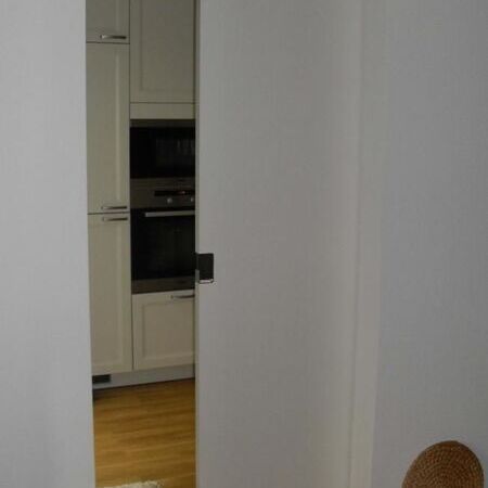 Weißlack-Schiebetür mit Design-Griff, in die Wand laufend