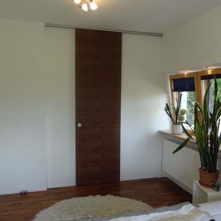 Raumhohe Holzschiebetür, Nussbaum quer furniert als Abschluss für begehbaren Kleiderschrank, Tür geschlossen