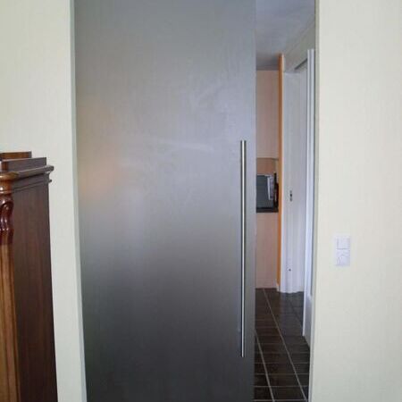 Raumhohe satinierte Glasschiebetür mit sichtbarem Design-Rollensystem, an der Decke befestigt