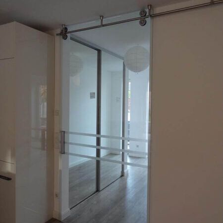 Raumhohe Glasschiebetür mit sichtbarem Design-Rollensystem