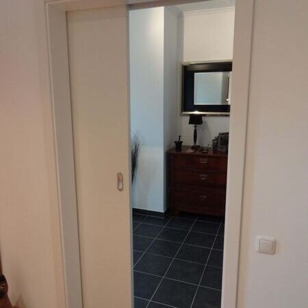 Vor der Wand laufende Weißlack-Schiebetür mit aufgesetztem Spiegel, Ansicht Raumseite